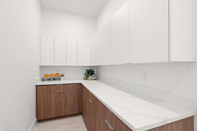 bar featuring light stone countertops and white cabinetry