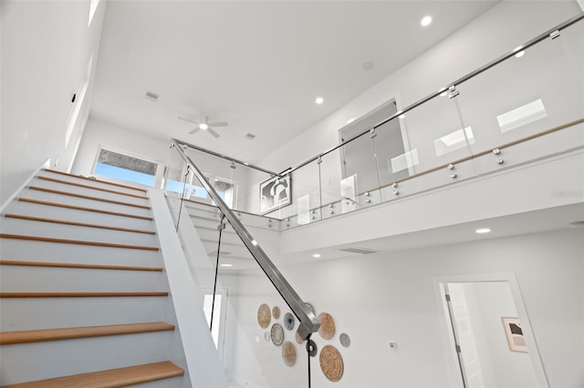 stairway featuring ceiling fan and a skylight