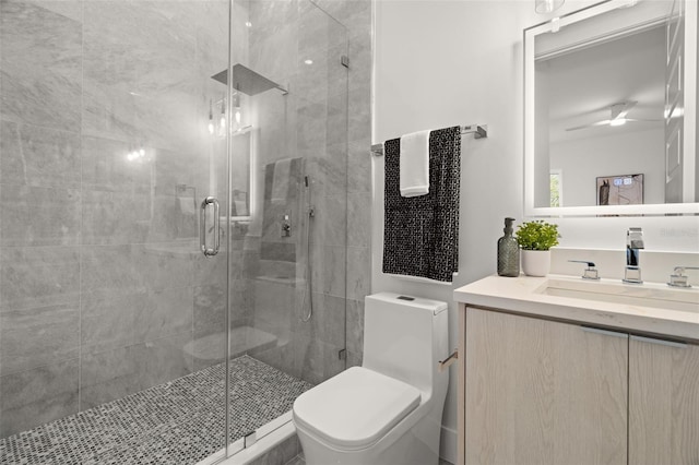 bathroom with toilet, vanity, a shower with door, and ceiling fan