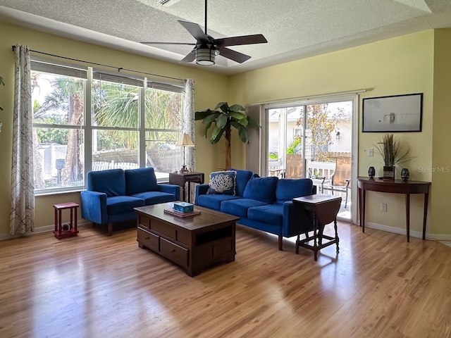 living room with ceiling fan, a textured ceiling, a wealth of natural light, and light hardwood / wood-style flooring