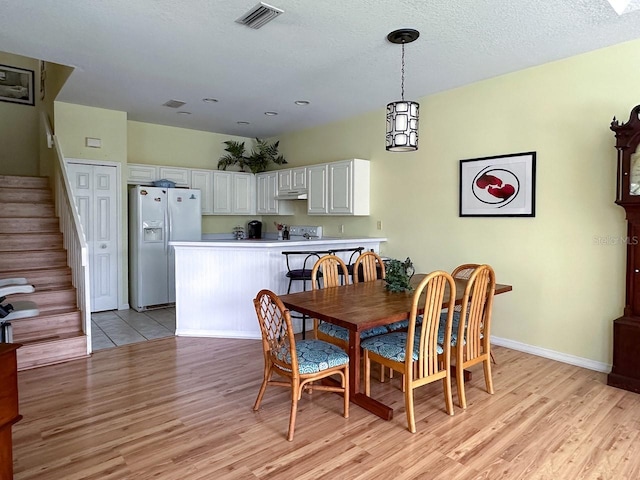 dining space with a textured ceiling and light hardwood / wood-style floors