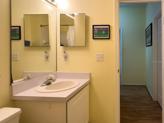 bathroom with toilet, vanity, and hardwood / wood-style flooring