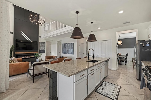 kitchen featuring white cabinetry, sink, an island with sink, and pendant lighting