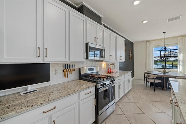 kitchen with white cabinets, decorative light fixtures, and stainless steel appliances