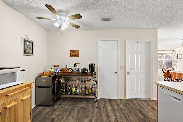 bar with white appliances, ceiling fan, dark wood-type flooring, and a textured ceiling