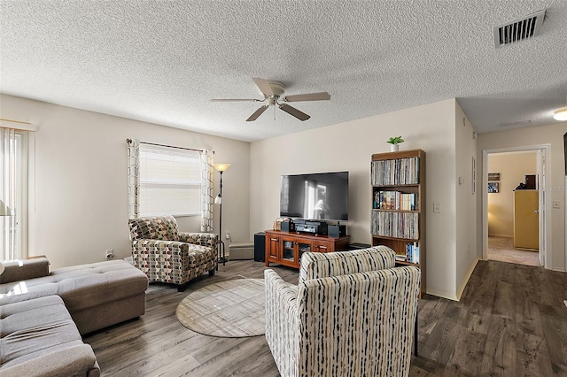 living room featuring a textured ceiling, hardwood / wood-style flooring, baseboard heating, and ceiling fan