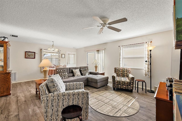 living room featuring wood-type flooring, a textured ceiling, and ceiling fan