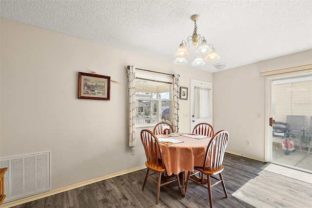 dining room with a textured ceiling, dark wood-type flooring, and an inviting chandelier