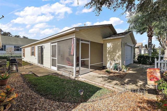 rear view of property featuring a garage and a sunroom