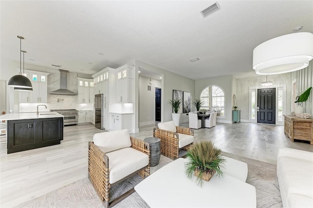 living room featuring sink, a textured ceiling, and light hardwood / wood-style flooring