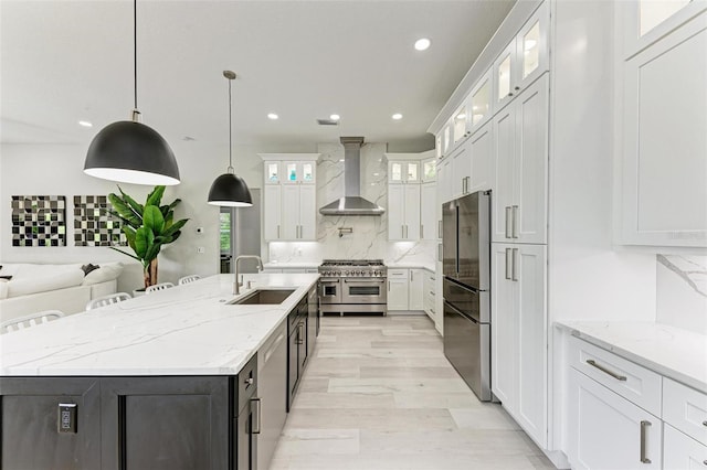 kitchen with stainless steel appliances, wall chimney exhaust hood, a large island, white cabinetry, and decorative light fixtures