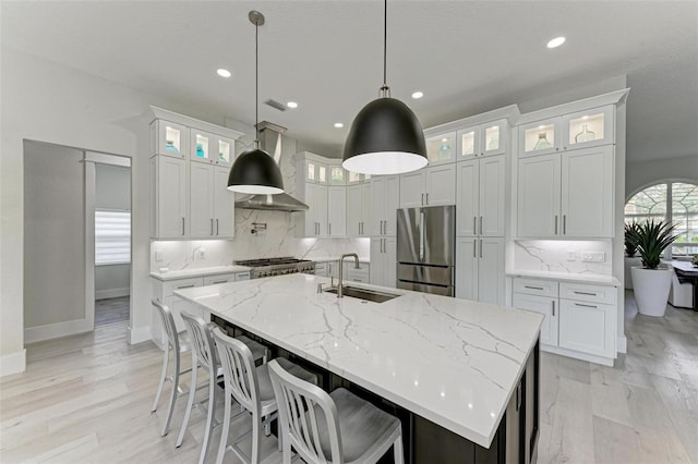 kitchen with sink, decorative light fixtures, an island with sink, white cabinets, and stainless steel fridge