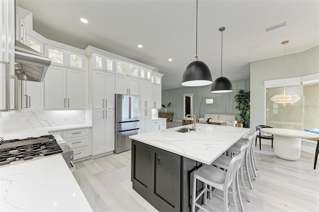 kitchen featuring white cabinets, an island with sink, decorative light fixtures, and appliances with stainless steel finishes