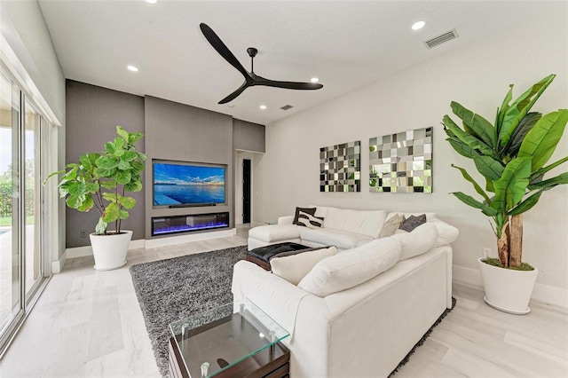 living room featuring a premium fireplace, ceiling fan, and light hardwood / wood-style floors