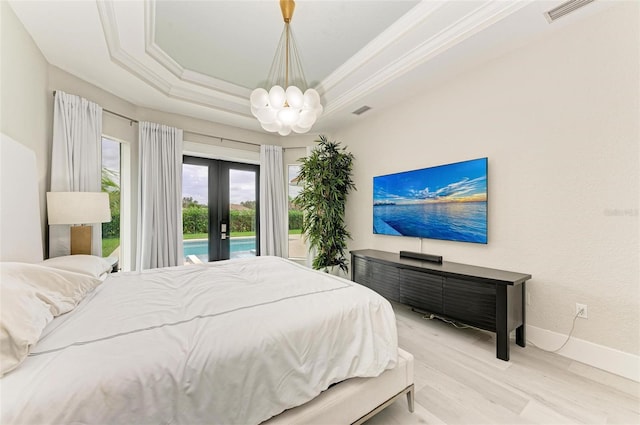 bedroom with french doors, crown molding, light wood-type flooring, a raised ceiling, and a chandelier