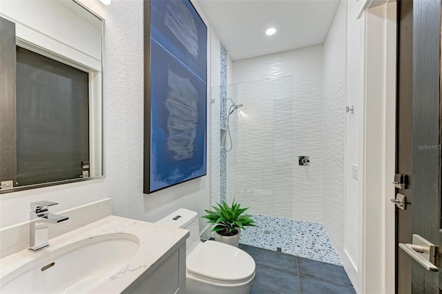 bathroom featuring tile patterned floors, vanity, toilet, and tiled shower