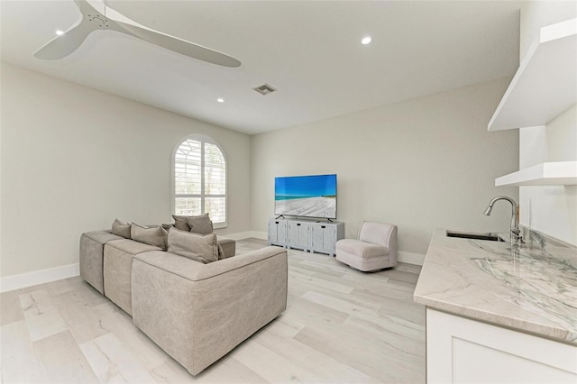 living room featuring light hardwood / wood-style flooring, sink, and ceiling fan