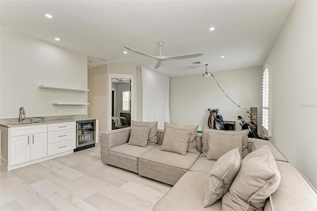 living room featuring beverage cooler, light hardwood / wood-style floors, sink, and ceiling fan