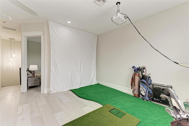 basement featuring golf simulator and hardwood / wood-style floors