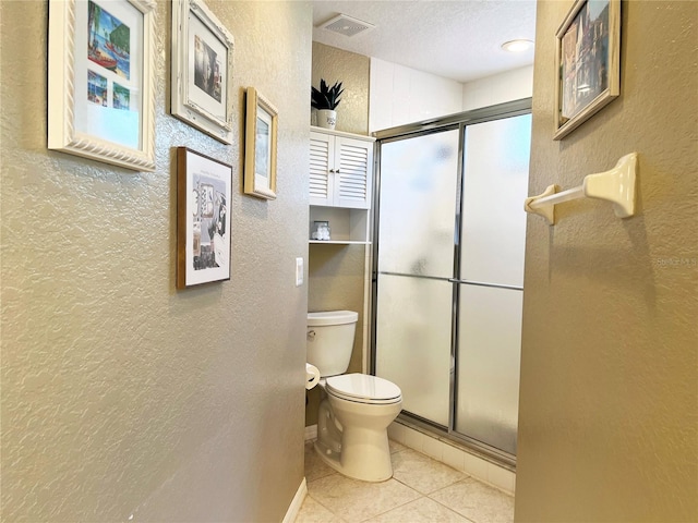 bathroom featuring tile patterned floors, a shower with shower door, a textured ceiling, and toilet