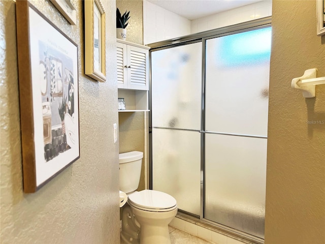 bathroom featuring toilet and a shower with shower door