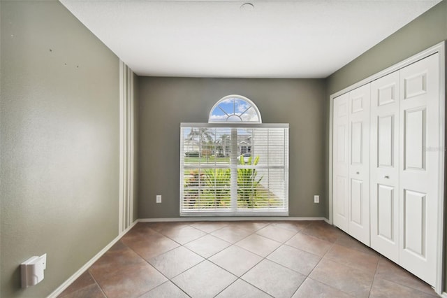 unfurnished bedroom featuring light tile patterned floors and a closet