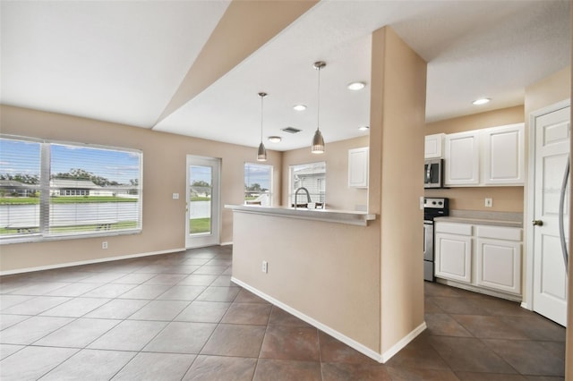 kitchen featuring white cabinetry, dark tile patterned flooring, stainless steel appliances, and decorative light fixtures