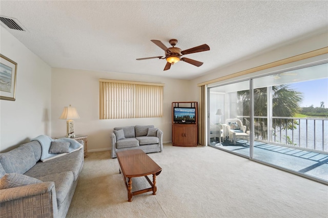 living room with a textured ceiling, light colored carpet, and ceiling fan