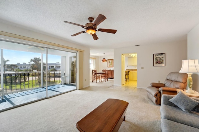 living room featuring a textured ceiling, light carpet, and ceiling fan