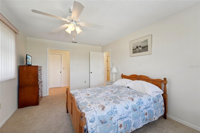 bedroom with a textured ceiling, light carpet, and ceiling fan