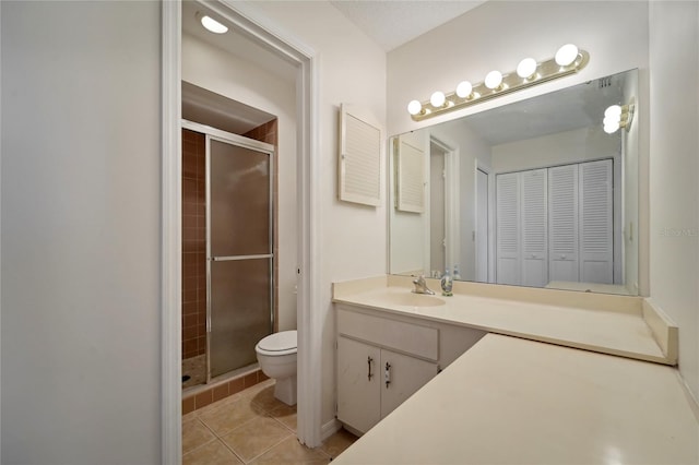 bathroom with tile patterned flooring, vanity, toilet, and a shower with shower door