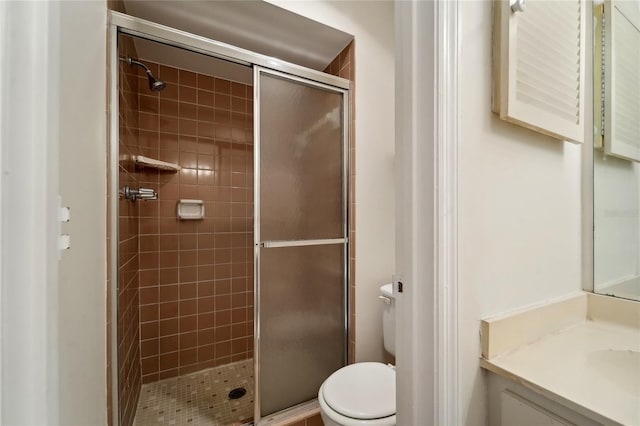 bathroom with toilet, vanity, and a shower with door