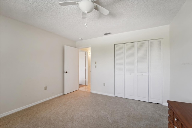 unfurnished bedroom with a closet, a textured ceiling, light carpet, and ceiling fan