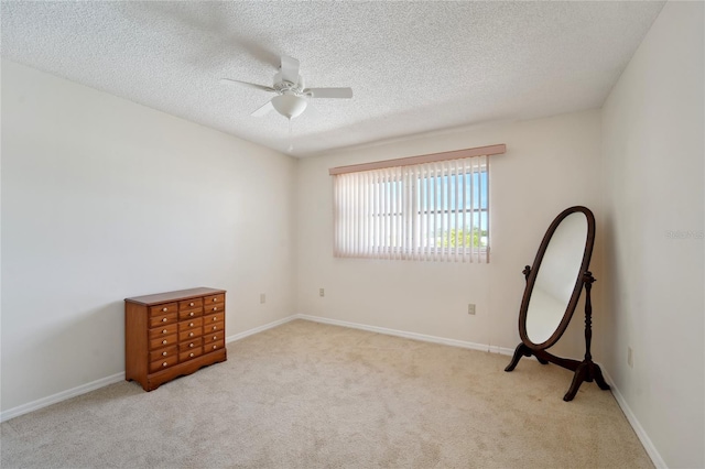 unfurnished room featuring a textured ceiling, light colored carpet, and ceiling fan