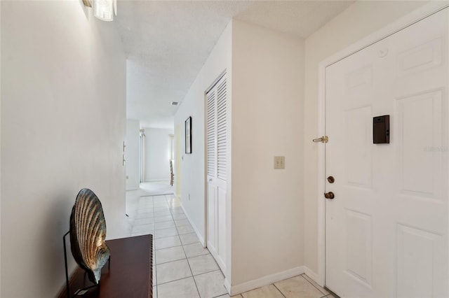 hall featuring a textured ceiling and light tile patterned flooring