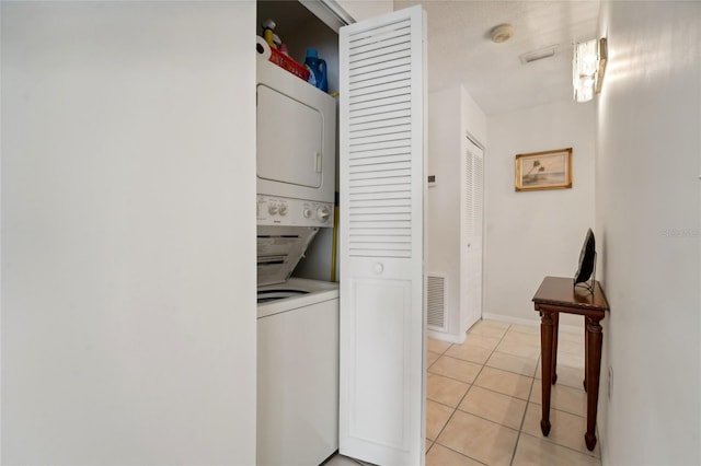 clothes washing area featuring light tile patterned floors and stacked washer / dryer