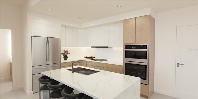 kitchen featuring stainless steel appliances, a center island with sink, light stone counters, and a breakfast bar area