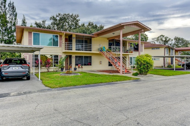 view of front facade with a front lawn, a balcony, and a carport