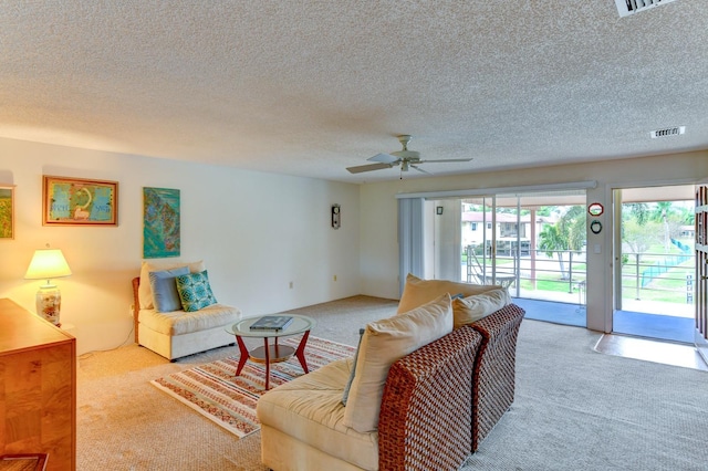 living room featuring a textured ceiling, light carpet, and ceiling fan