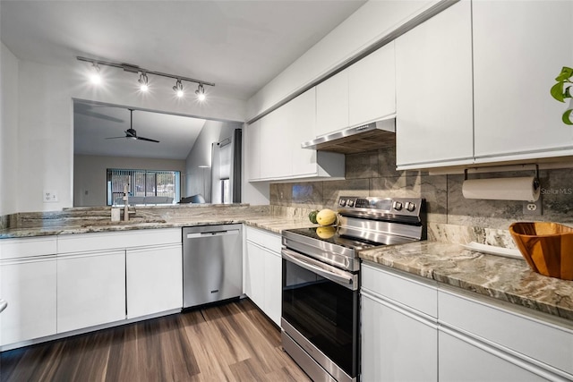 kitchen with vaulted ceiling, dark hardwood / wood-style floors, appliances with stainless steel finishes, white cabinetry, and extractor fan