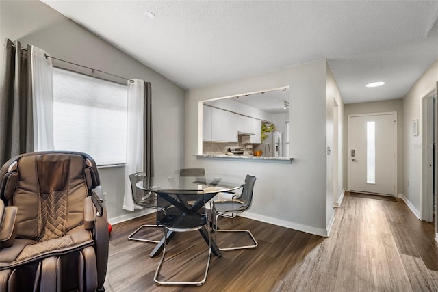 dining room with lofted ceiling, wood-type flooring, and a textured ceiling