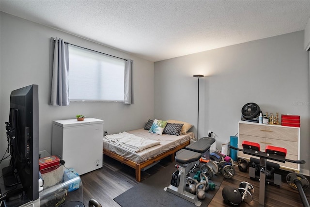 bedroom featuring a textured ceiling, refrigerator, and dark hardwood / wood-style floors