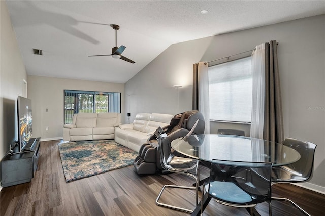 living room with a textured ceiling, dark hardwood / wood-style flooring, vaulted ceiling, and ceiling fan