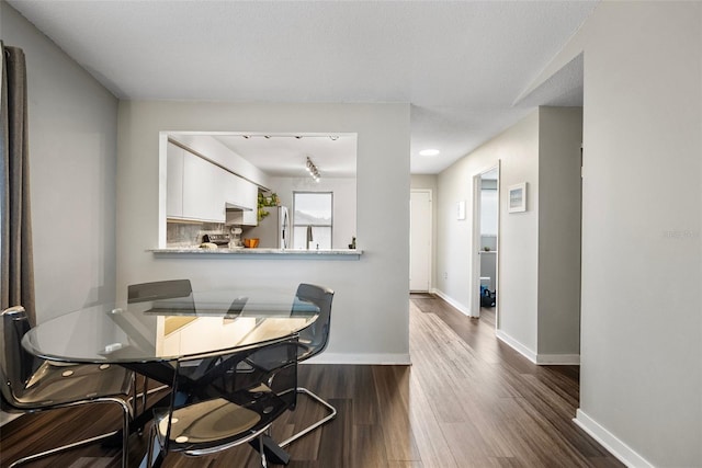 dining space with dark wood-type flooring and a textured ceiling