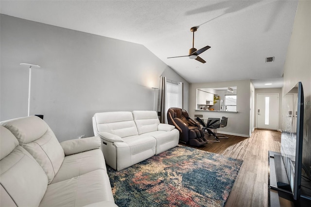 living room with hardwood / wood-style flooring, ceiling fan, a textured ceiling, and vaulted ceiling