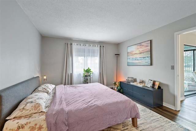 bedroom with dark hardwood / wood-style flooring, a textured ceiling, and access to outside