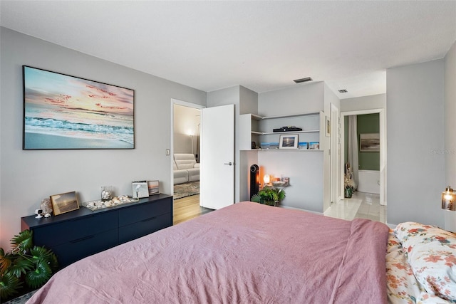 bedroom with connected bathroom and light hardwood / wood-style floors