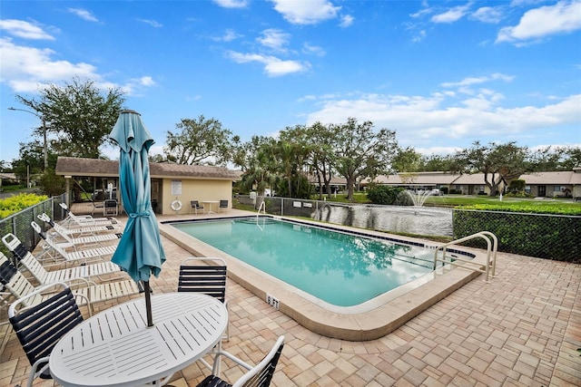 view of pool featuring a water view and a patio