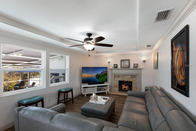 living room featuring ceiling fan, a raised ceiling, wood-type flooring, and ornamental molding