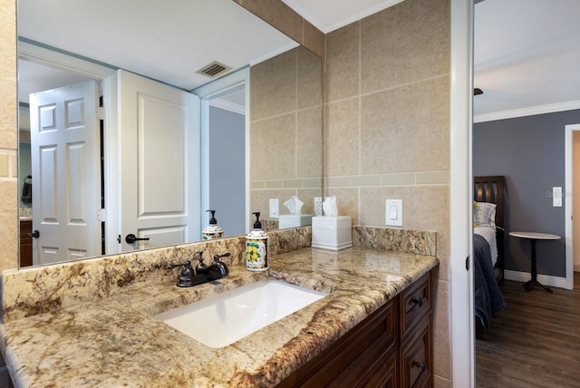 bathroom featuring hardwood / wood-style floors, vanity, crown molding, and tile walls